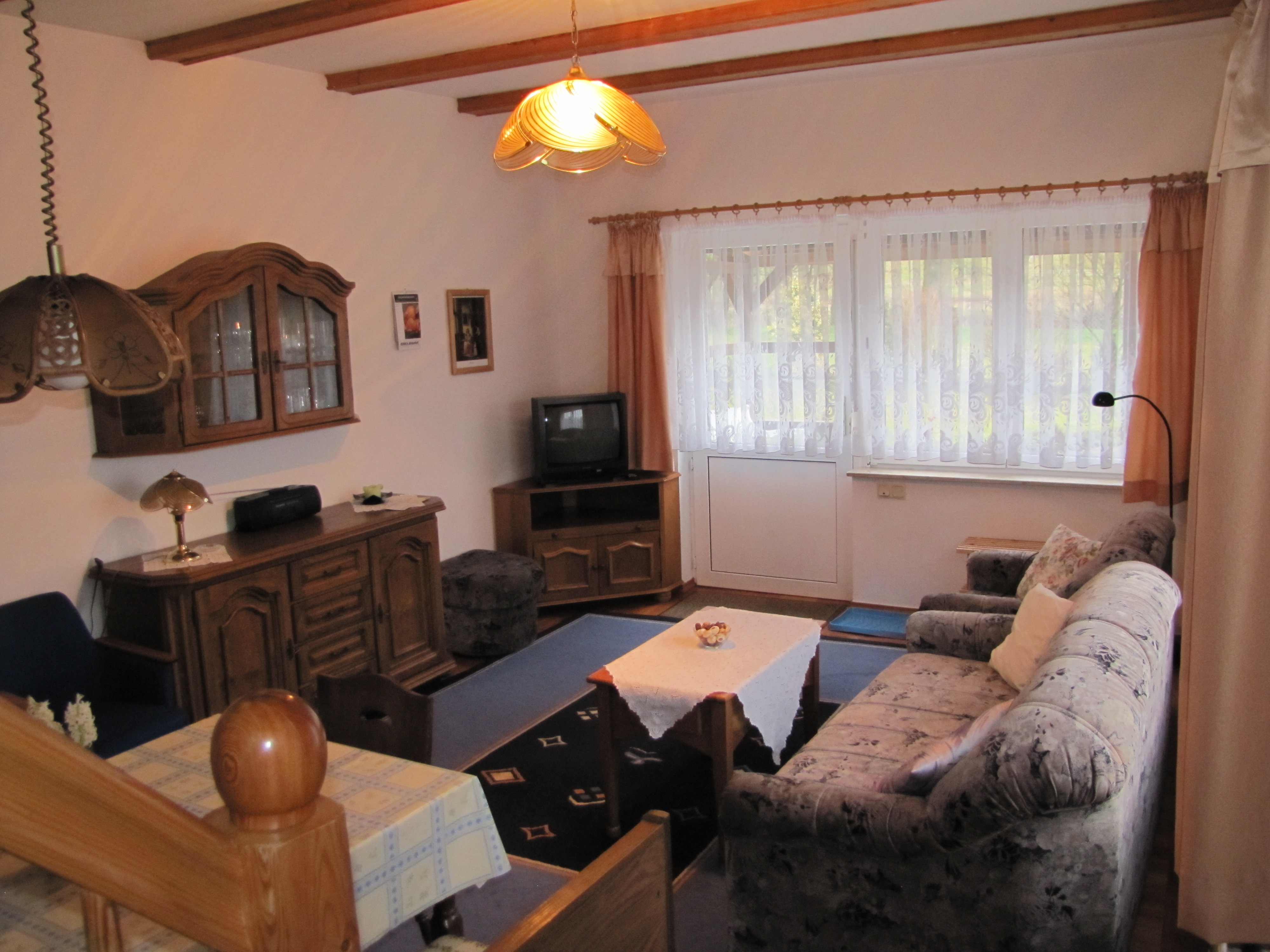 Wohnzimmer mit Couch, Couchtisch, Fernseher und Vitrine