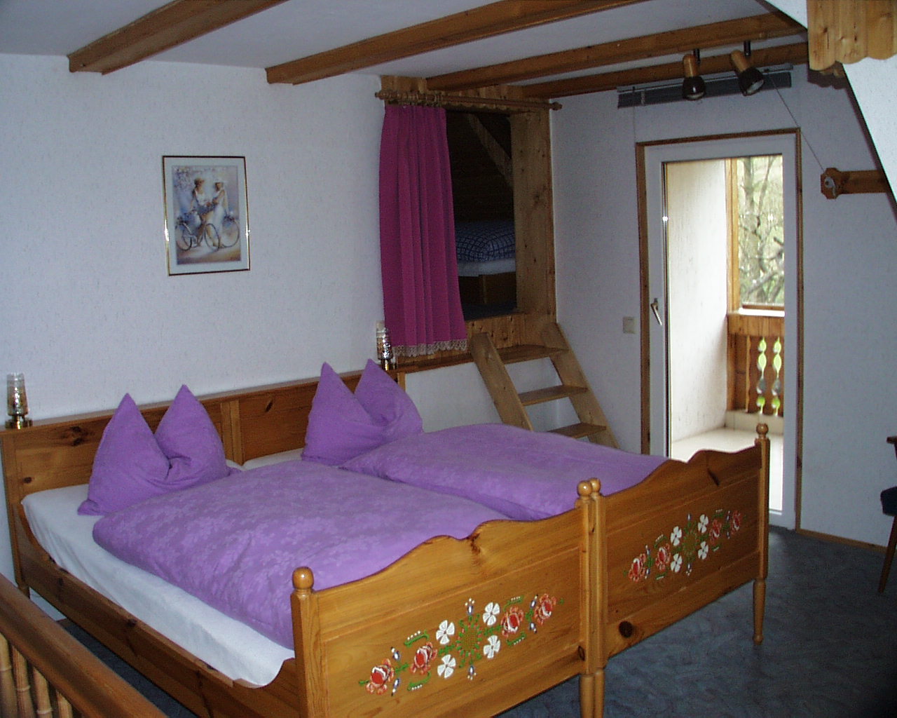 Schlafzimmer mit Doppelbett, lila Bettwäsche und Schlafgalerie